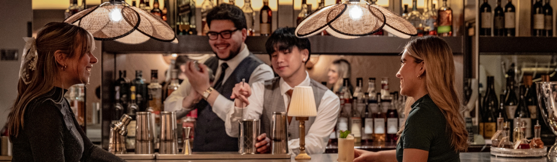 Two ladies enjoying cocktails at Rick’s Bar while the bartender prepares drinks in the background