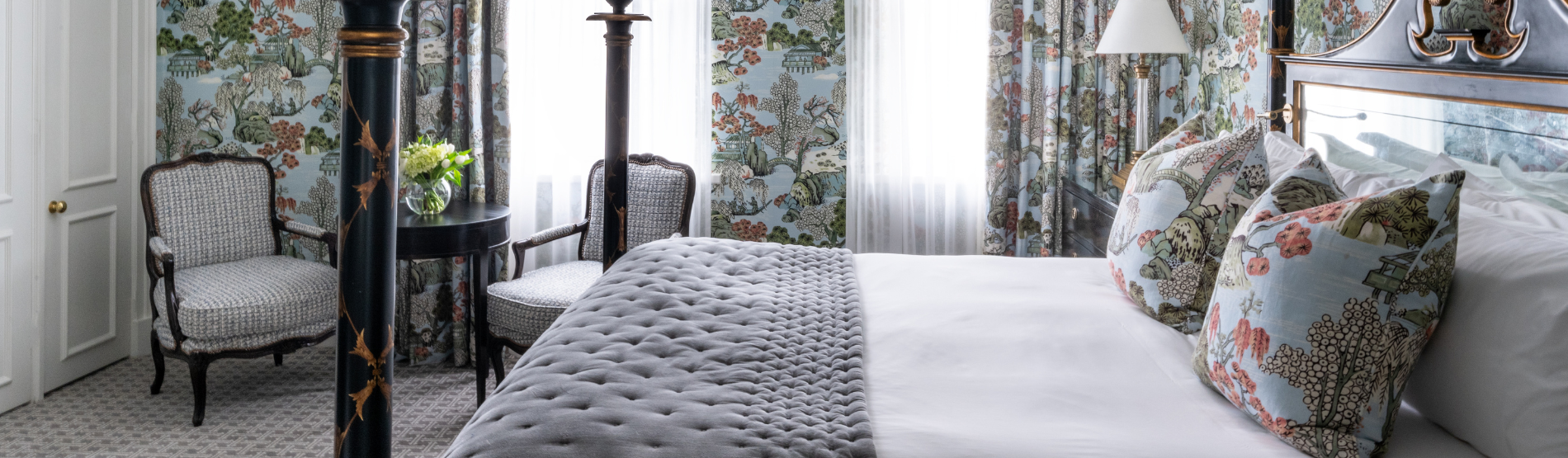 A sophisticated suite at the Kensington Hotel, with a comfortable bed and a beautiful bouquet of flowers on the table.