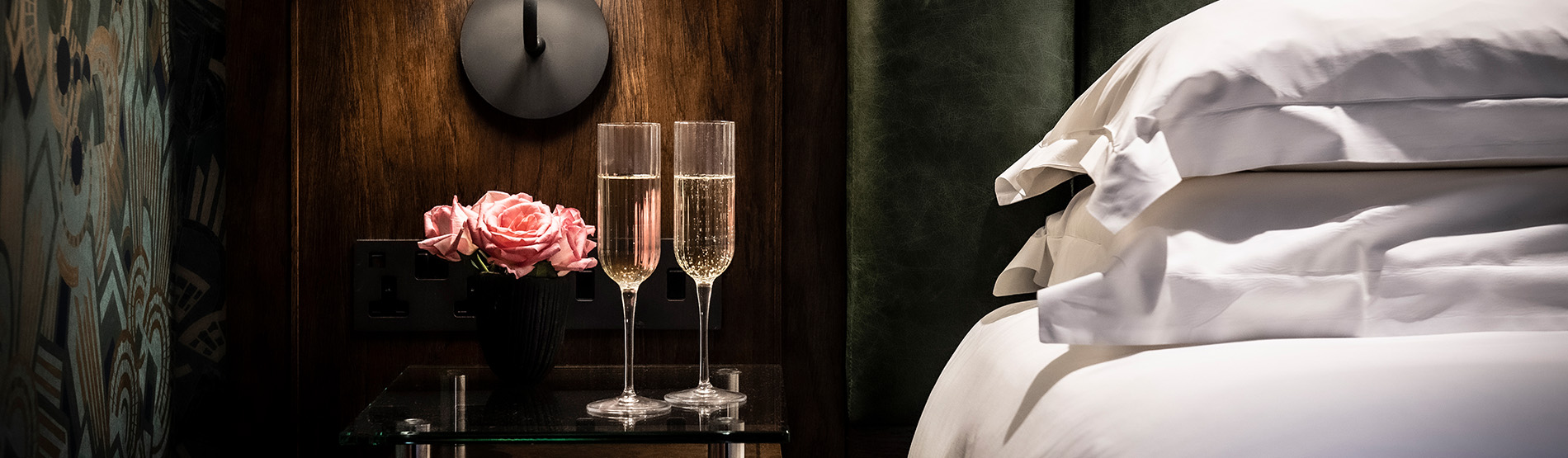 Two champagne glasses on a bedside table